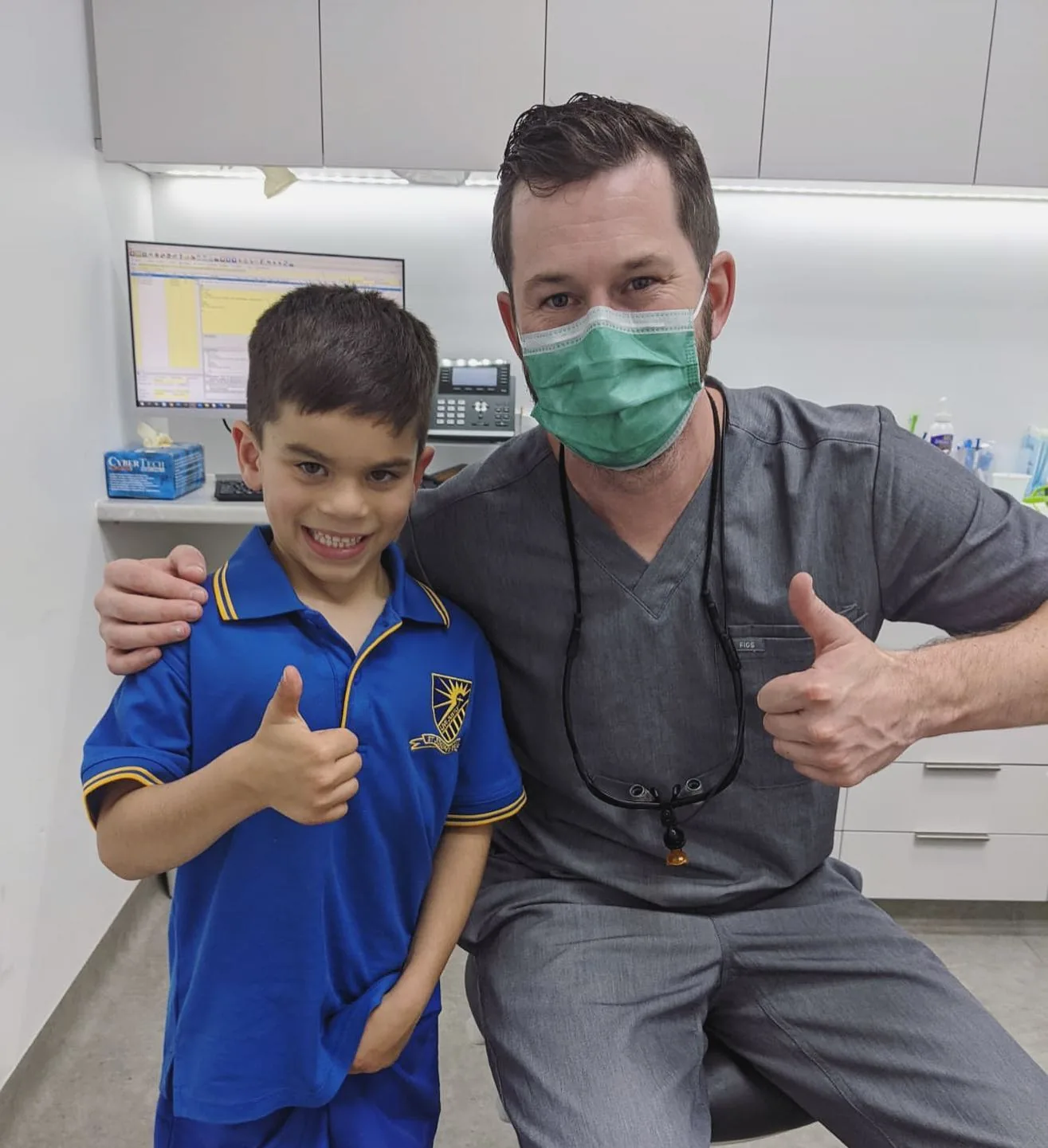A boy giving a thumbs up with his dentist after his first visit
