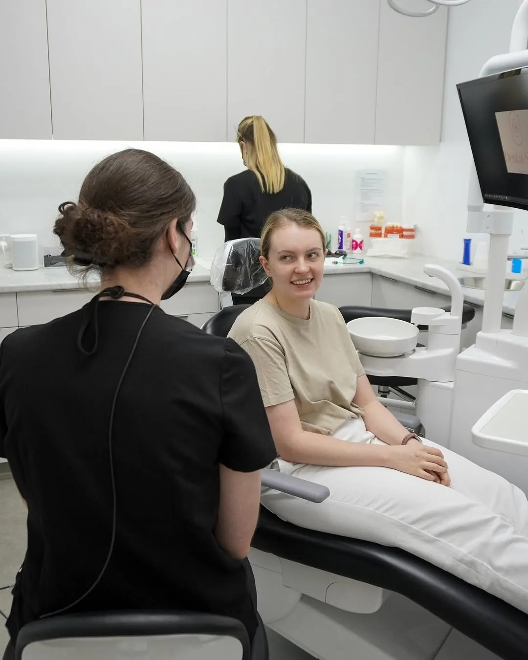 A patient smiling as she talks with her dentist in the dental chair